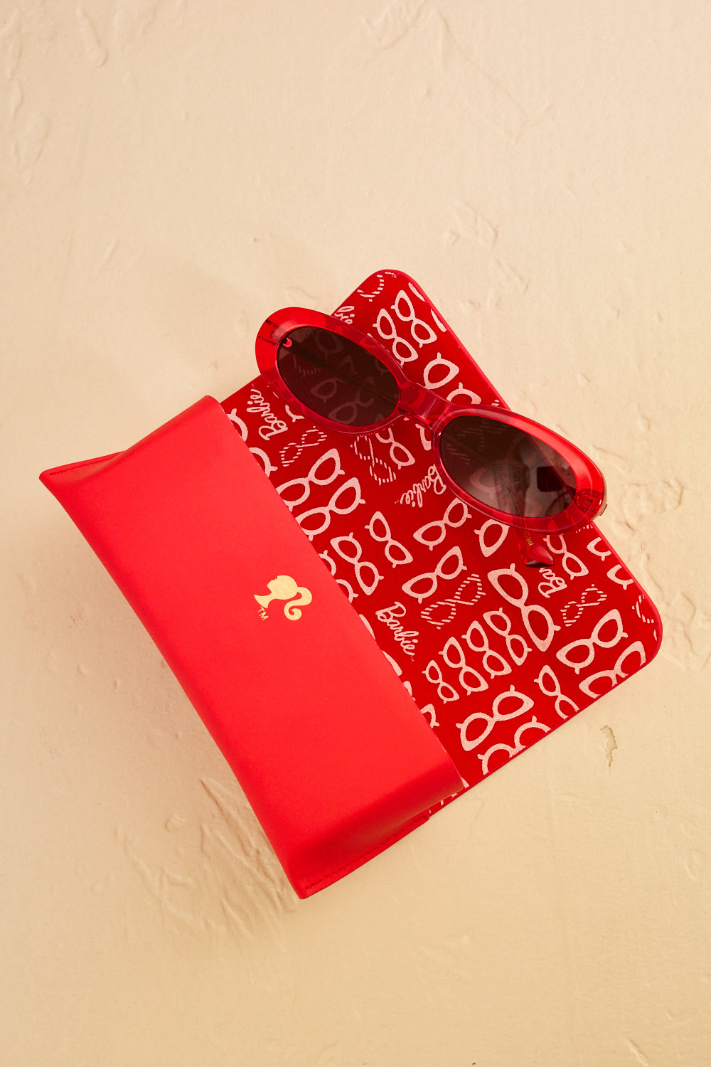 Barbie x Sol Kyst red sunglasses displayed with matching red case featuring Barbie-themed interior print.