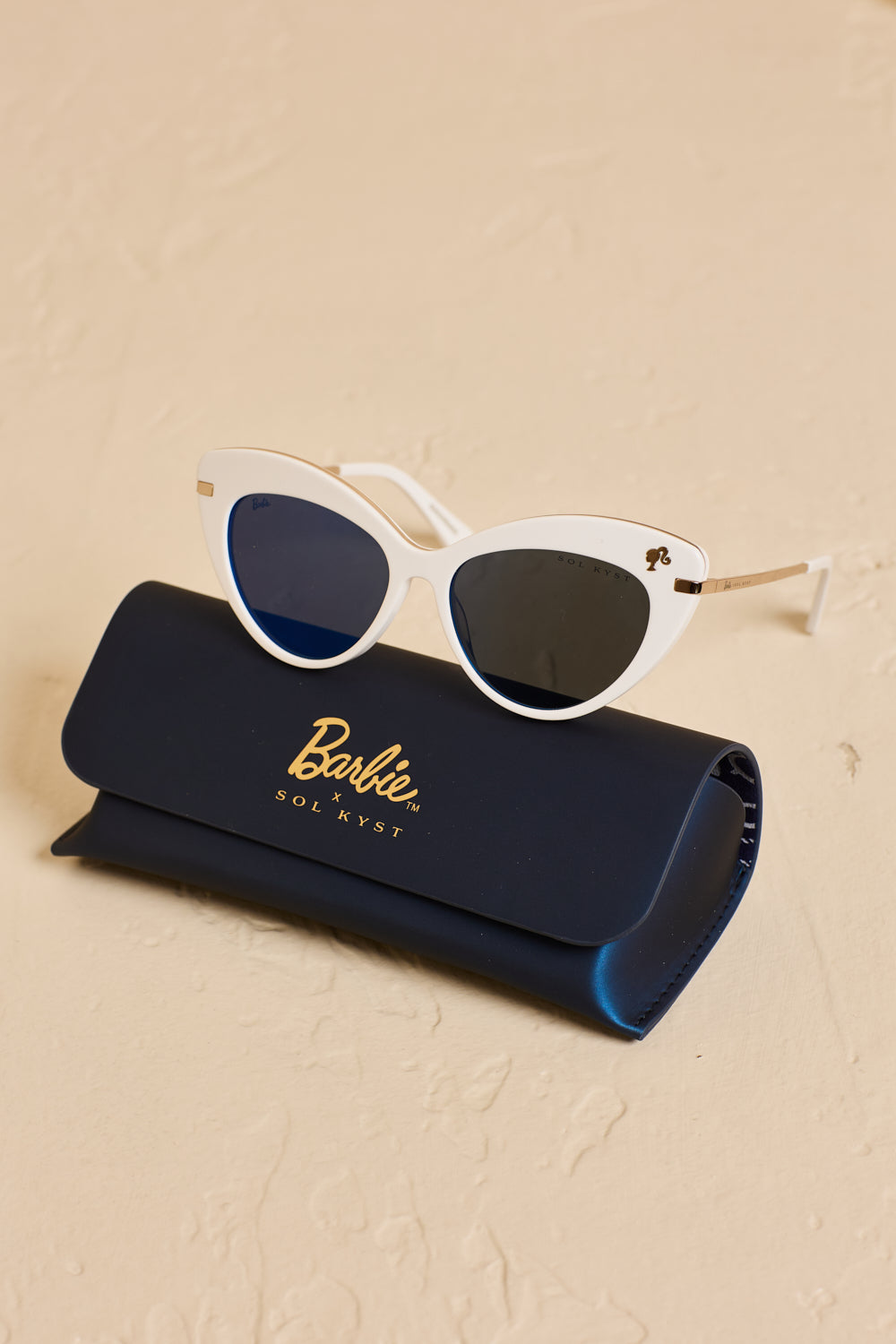 White Barbie cat eye sunglasses sitting on top of a matching "Barbie x SOL KYST" case.