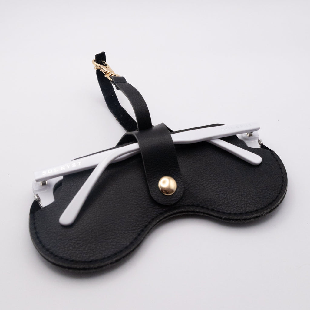 Back view of black Sol Kyst "Kyst Klip" holding sunglasses with white frames on a white background.